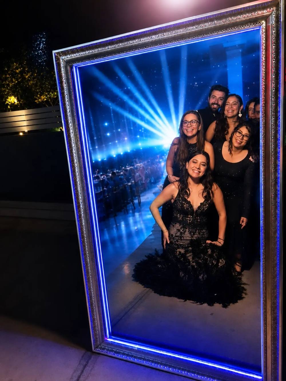 Grupo de invitados sonriendo dentro del espejo mágico Pikibooth con marco plateado y luz LED azul en un evento en Querétaro