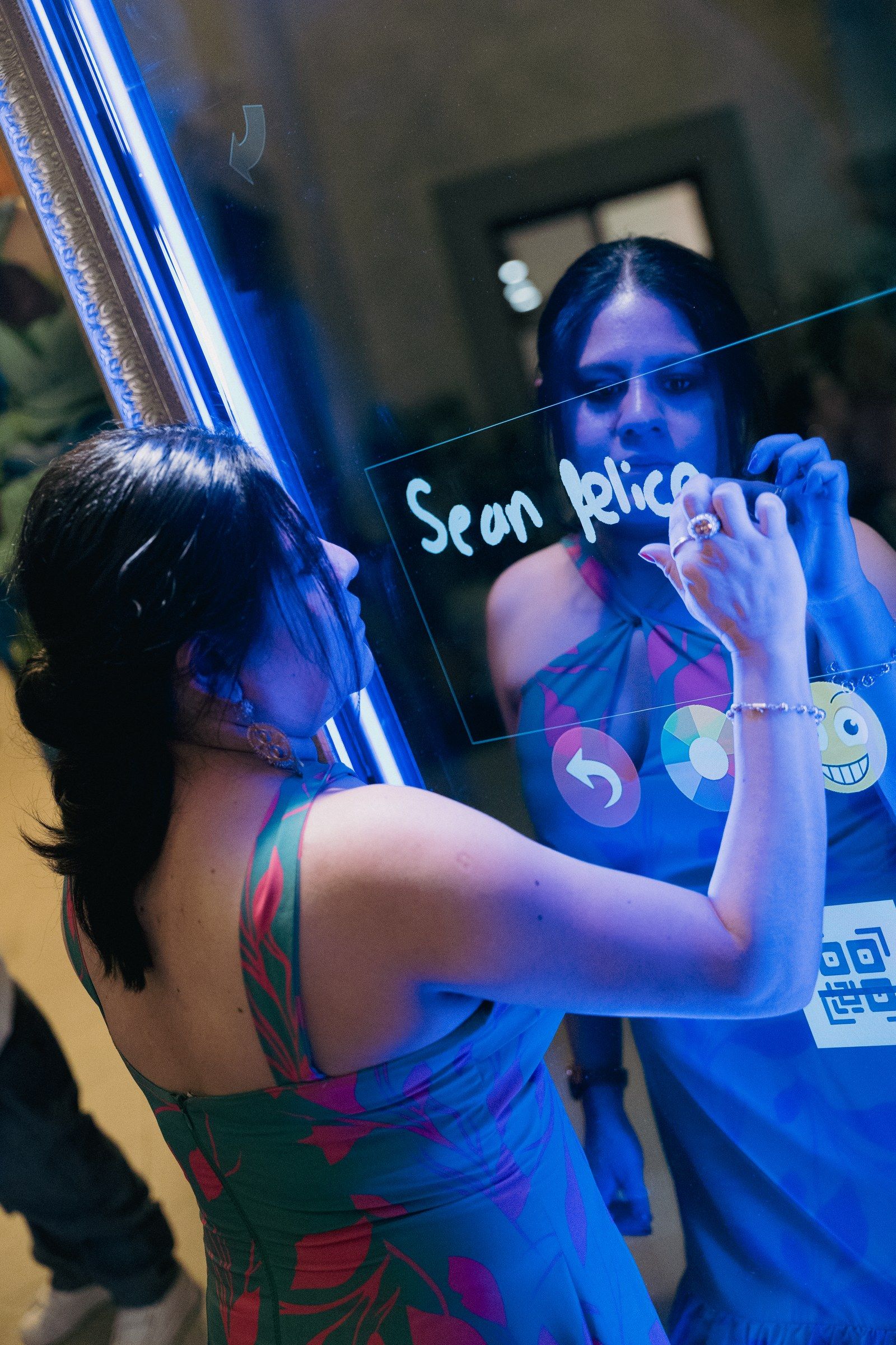 Invitada escribiendo Sean felices en la pantalla táctil del espejo mágico antes de imprimir su foto