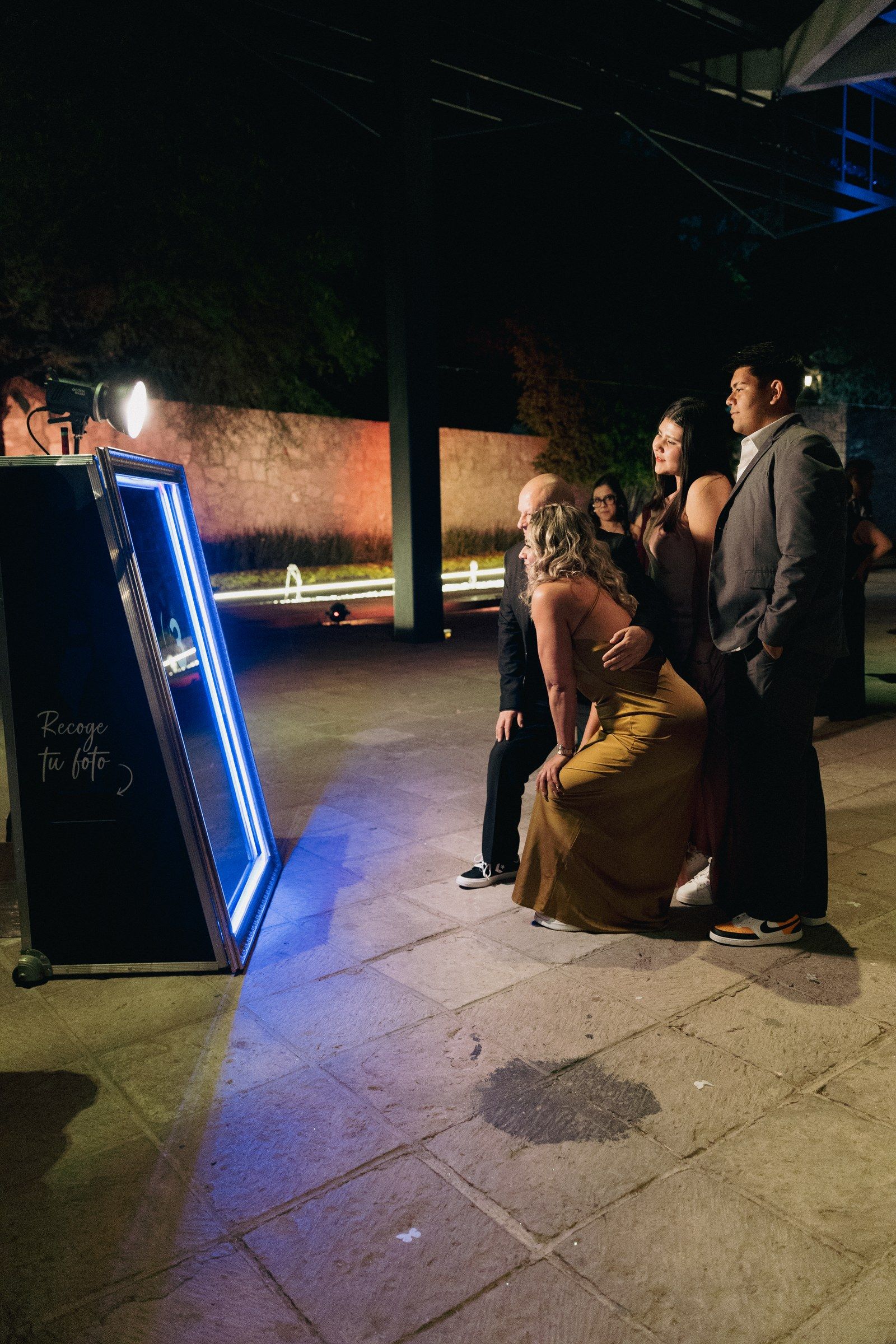 Familia posando frente al espejo mágico Pikibooth iluminado con luz de estudio en una terraza de eventos en Querétaro